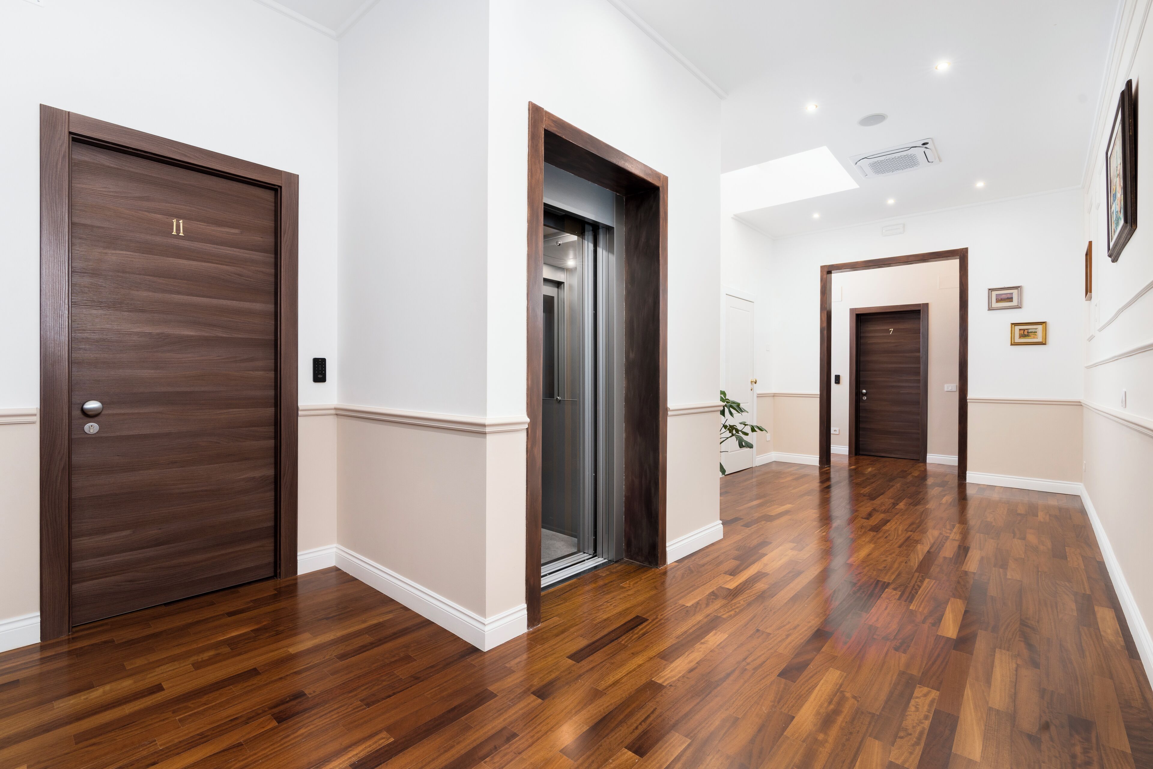 A hallway with wooden flooring, a sliding door, and a door with the number 11.