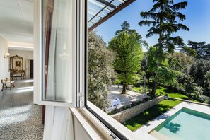 Une pièce dotée d’une grande fenêtre donnant sur un jardin et une piscine.