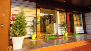 Un edificio moderno con techo de madera, puertas de cristal grandes y plantas en macetas en la entrada.