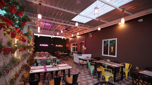 Un restaurante con varias mesas y sillas, piso de cuadros y luces colgantes.