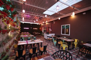 A restaurant with multiple tables and chairs, a checkered floor, and hanging lights.