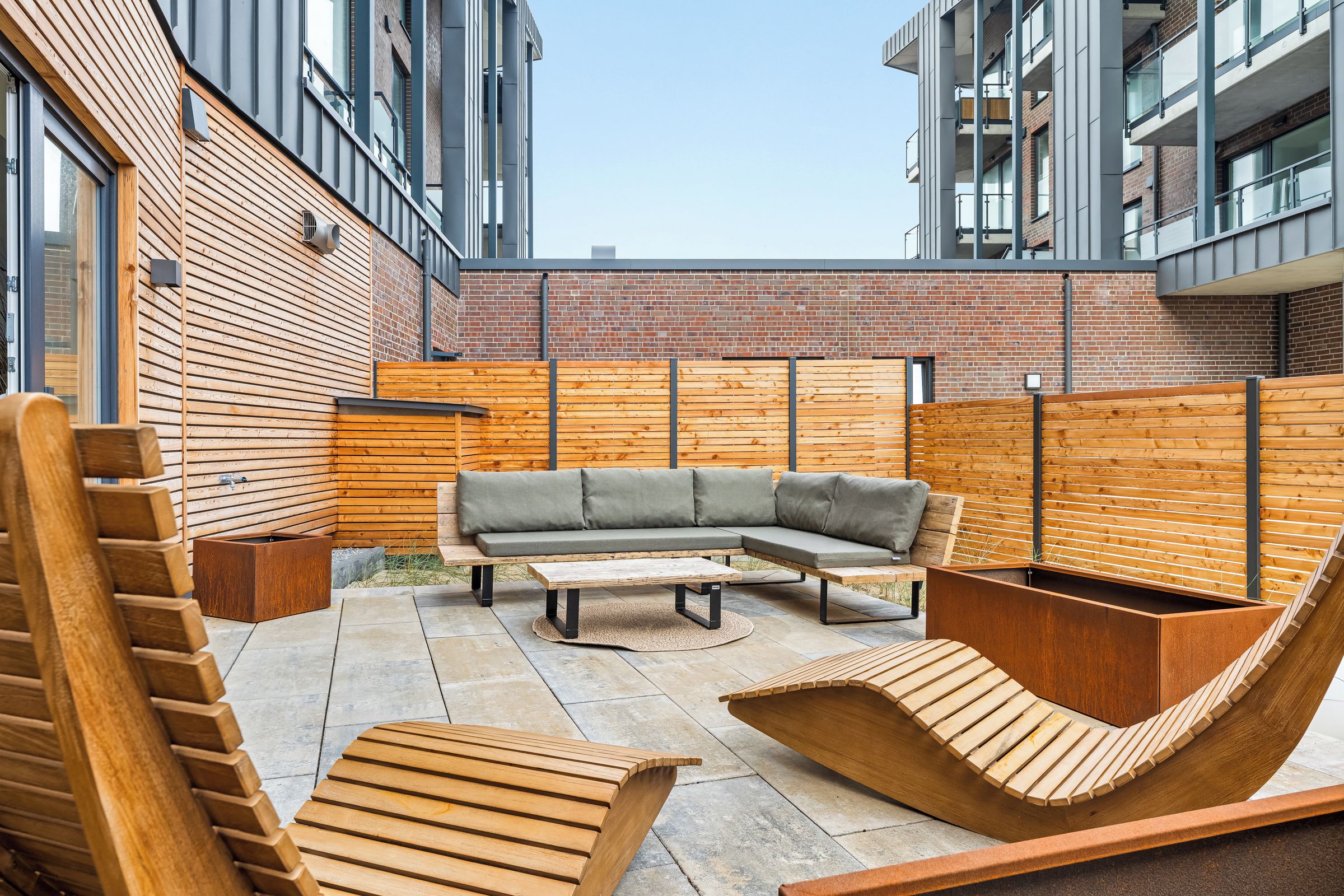 An outdoor seating area with a wooden bench, a sofa, and a coffee table.