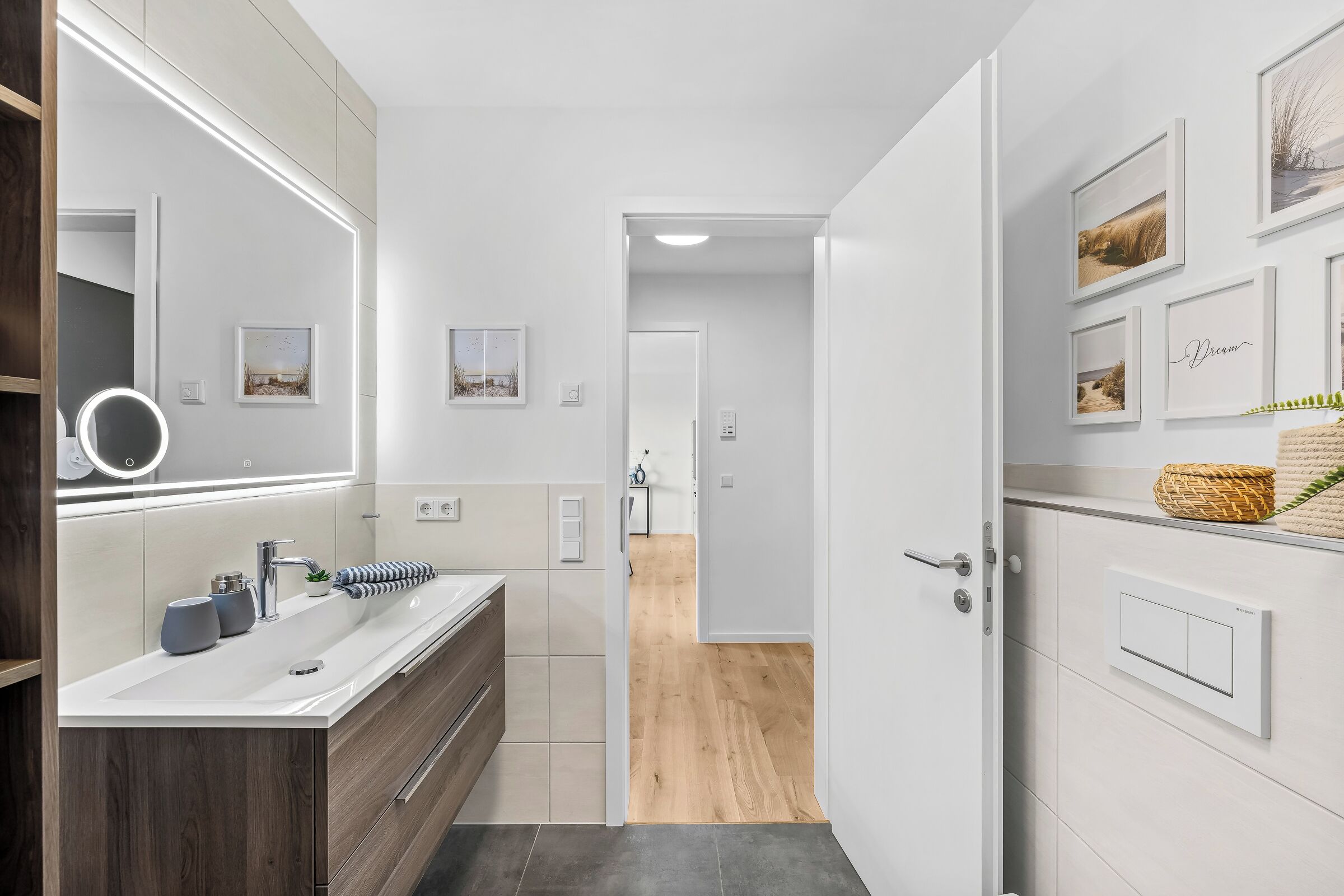A modern bathroom with a vanity, mirror, and wall-mounted lights.
