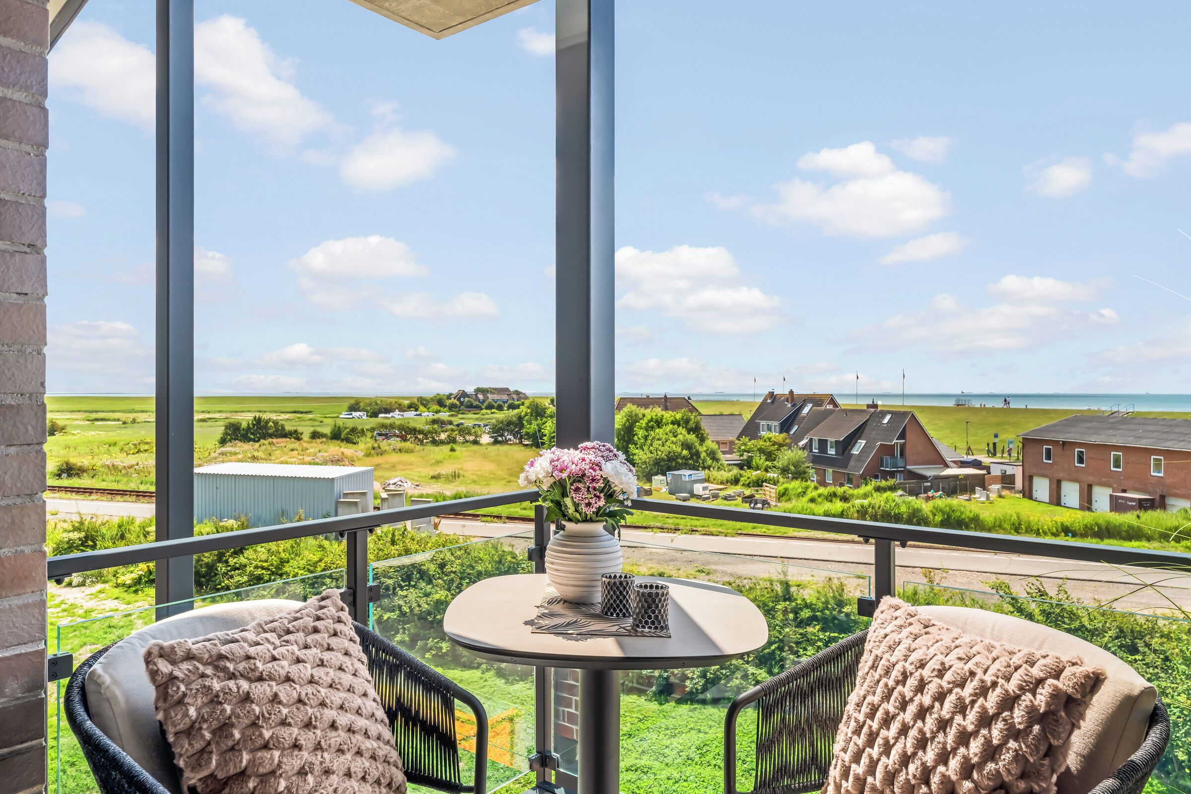 Ein Balkon mit Tisch, zwei Stühlen und einem Blumenstrauß.