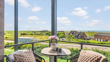 Ein Balkon mit Tisch, zwei Stühlen und einem Blumenstrauß.