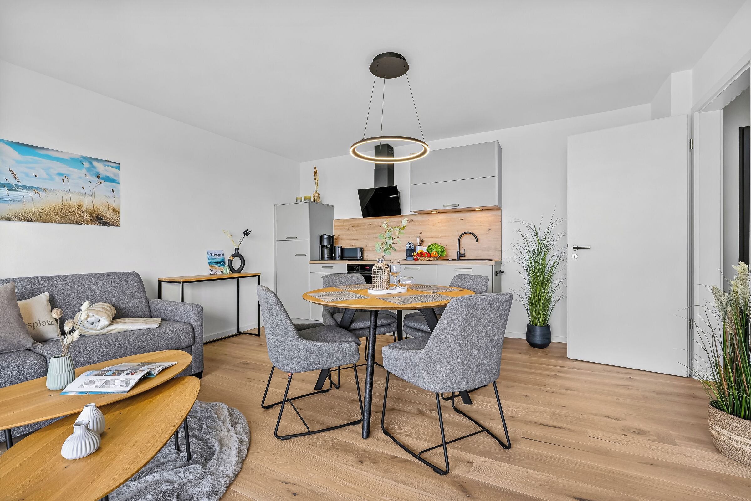 Een moderne woonkamer met een bank, salontafel en eethoek.