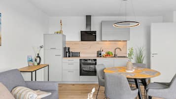 Eine moderne Küche mit Essbereich, ausgestattet mit einem Backofen, einer Kaffeemaschine und einer Holzarbeitsplatte.