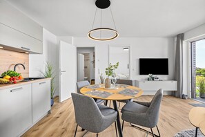 Une cuisine moderne avec un coin repas, un téléviseur à écran plat et une vue sur l’extérieur.
