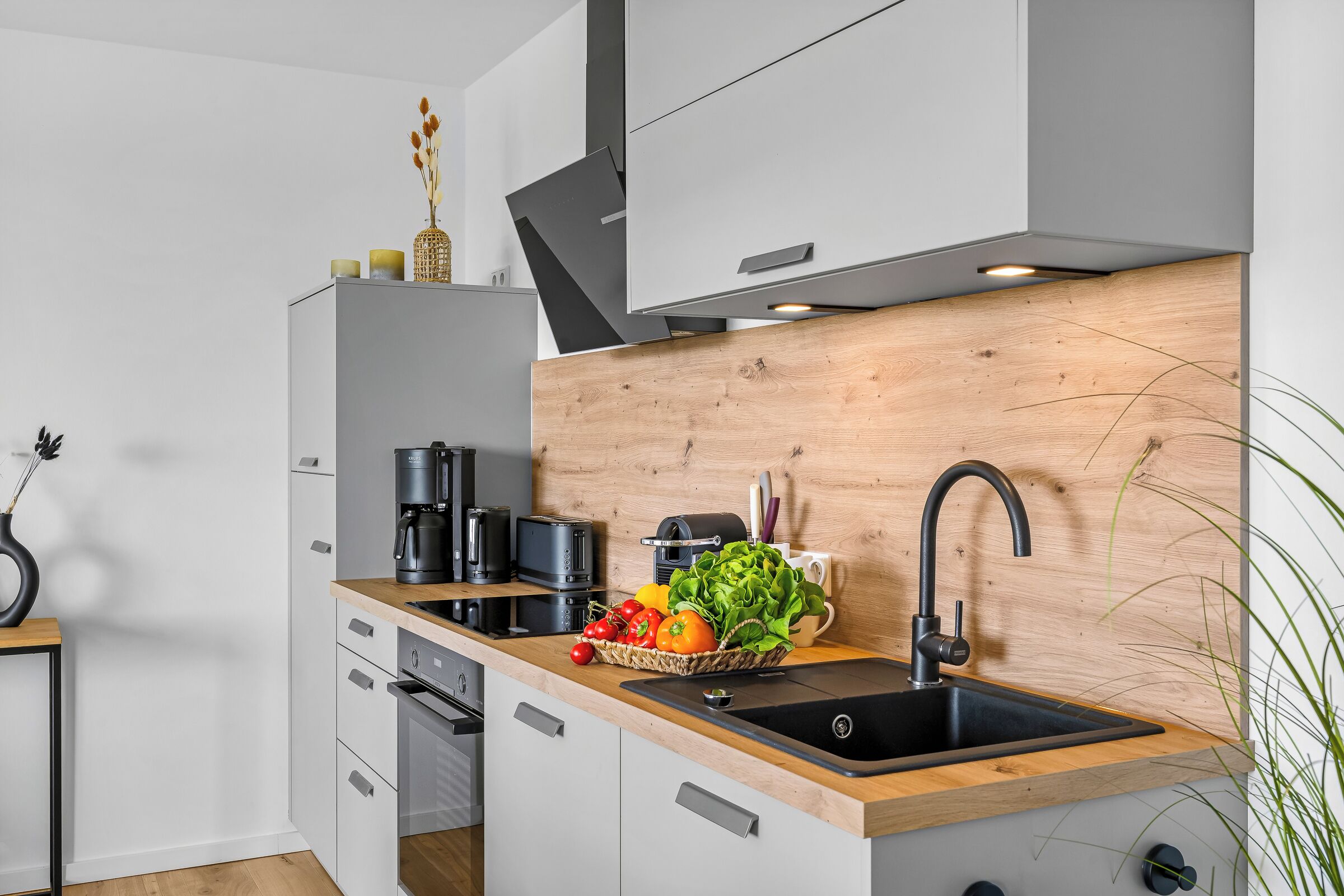 Eine moderne Küche mit einer Holzausstattung, einem Spülbecken und verschiedenen Geräten, darunter eine Kaffeemaschine und ein Toaster.