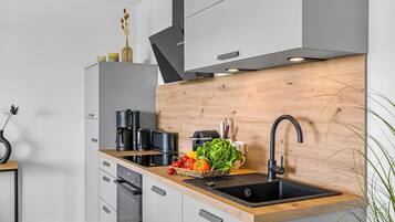Eine moderne Küche mit einer Holzausstattung, einem Spülbecken und verschiedenen Geräten, darunter eine Kaffeemaschine und ein Toaster.
