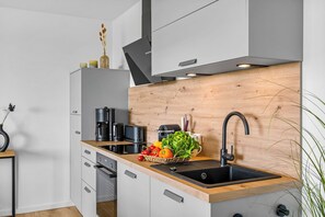 Eine moderne Küche mit einer Holzausstattung, einem Spülbecken und verschiedenen Geräten, darunter eine Kaffeemaschine und ein Toaster.