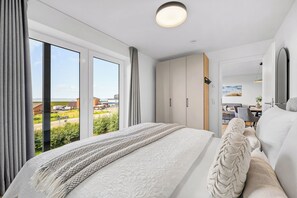 Quarto moderno com cama grande, guarda-roupa e vista para o exterior.