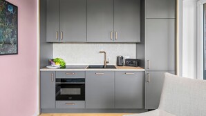 Uma cozinha moderna com armários cinza, forno embutido e máquina de café.