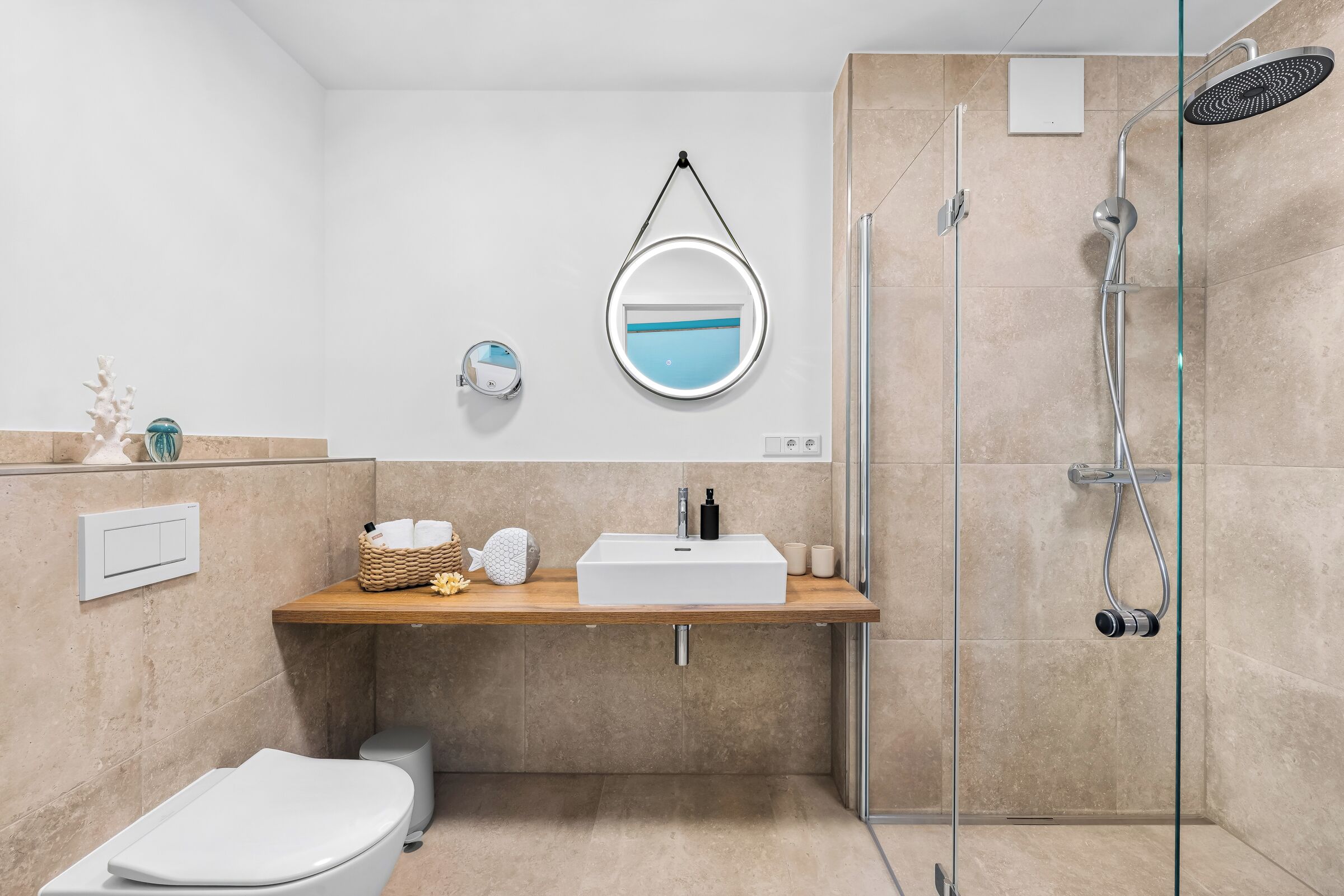 Ein modernes Badezimmer mit Duschkabine aus Glas, einem hölzernen Waschtisch, einer weißen Toilette und einem wandmontierten Spiegel.