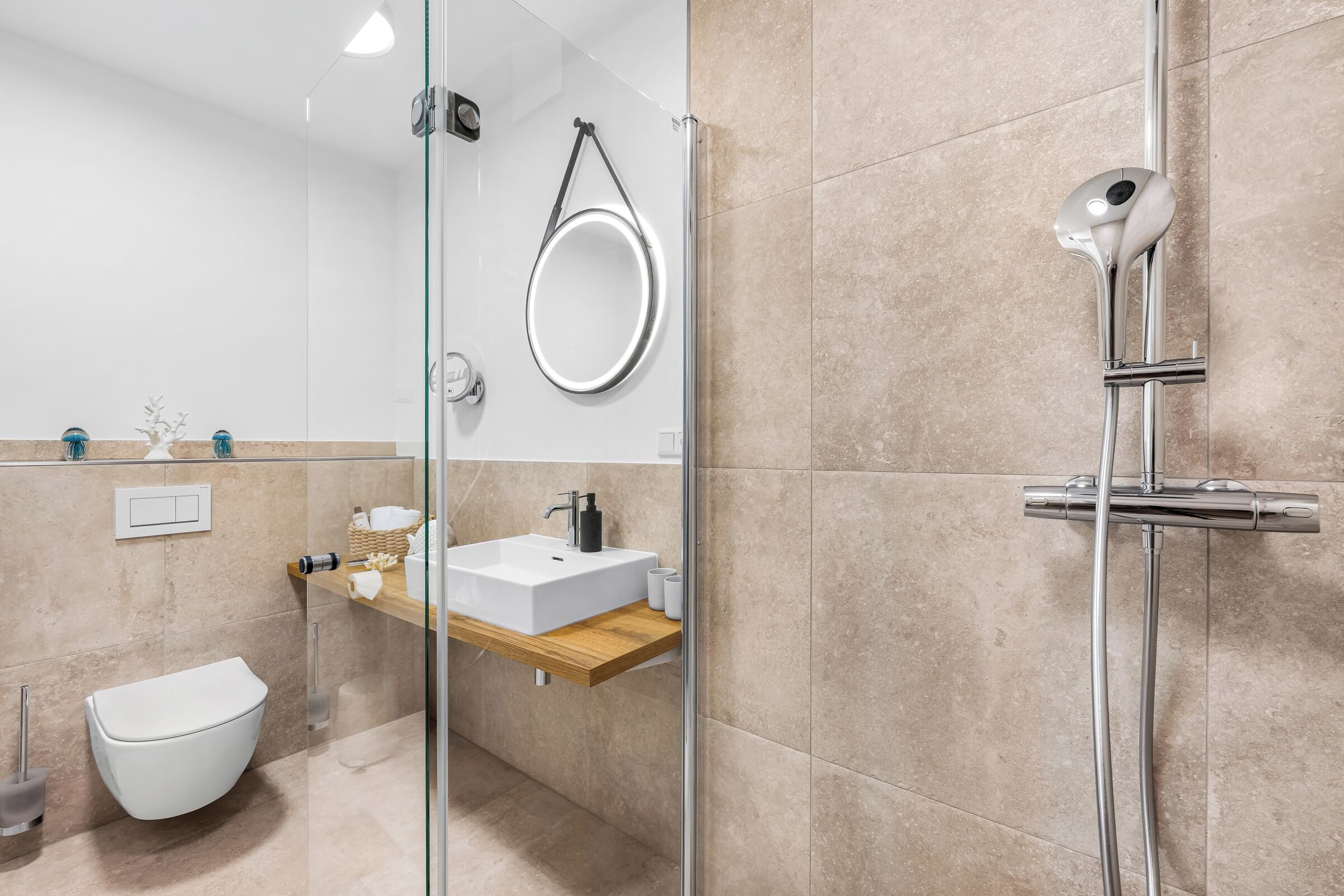 A modern bathroom with a glass shower enclosure, a white sink, and a toilet.