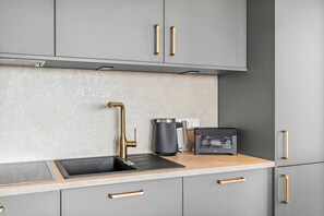 A modern kitchen with grey cabinets, a stainless steel sink, and a coffee machine.
