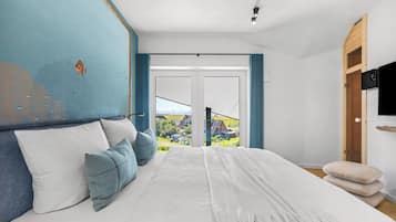 Ett sovrum med en stor säng, utsikt över ett bostadsområde och en garderob i trä.