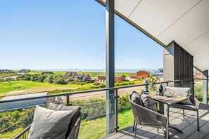 A balcony with a view of a coastal landscape, including houses and a road.