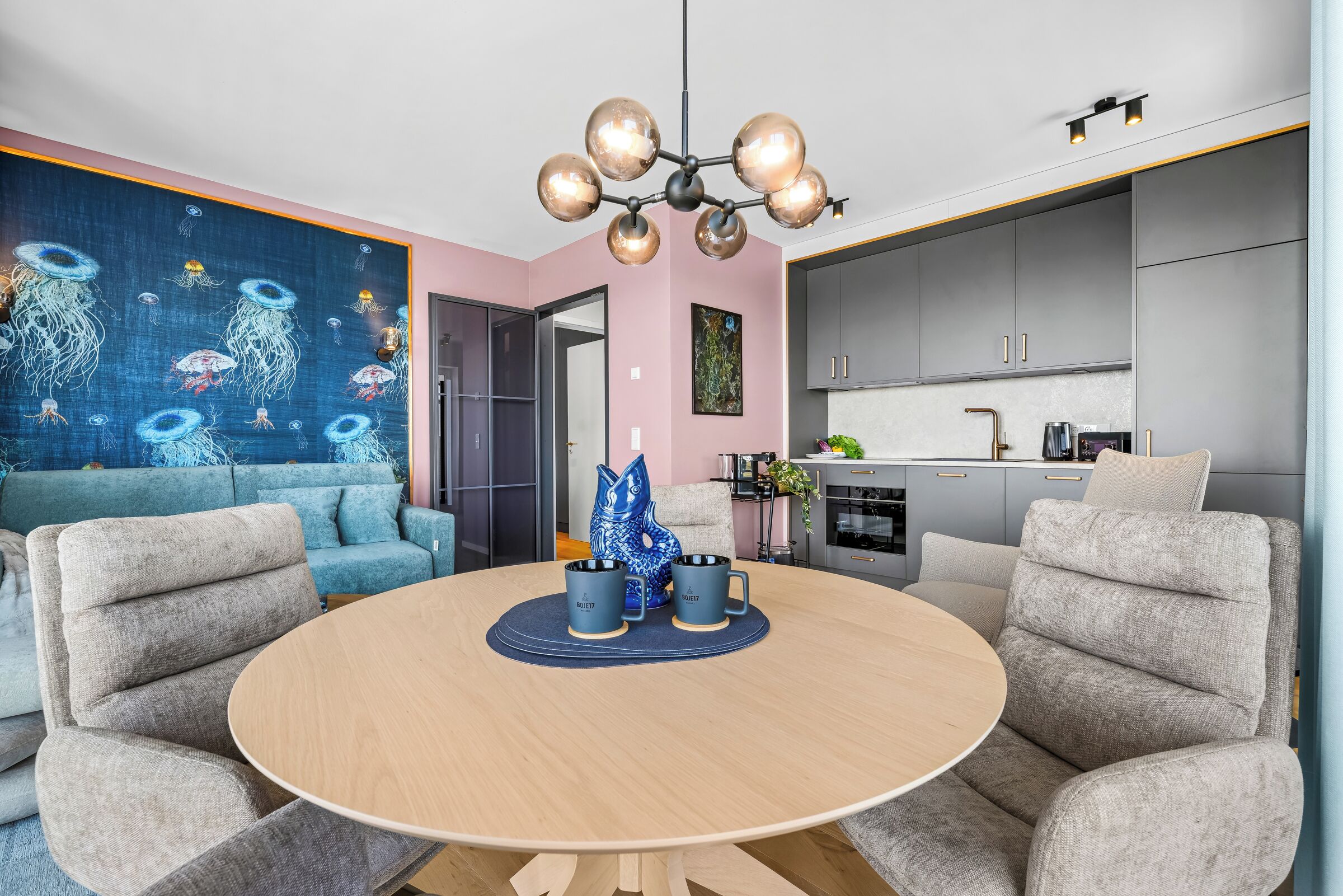 Ein modernes Wohnzimmer mit rundem Tisch, grauen Sofas und einem blauen, abstrakten Gemälde an der Wand.
