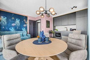 A modern living room with a round table, grey sofas, and a blue abstract painting on the wall.