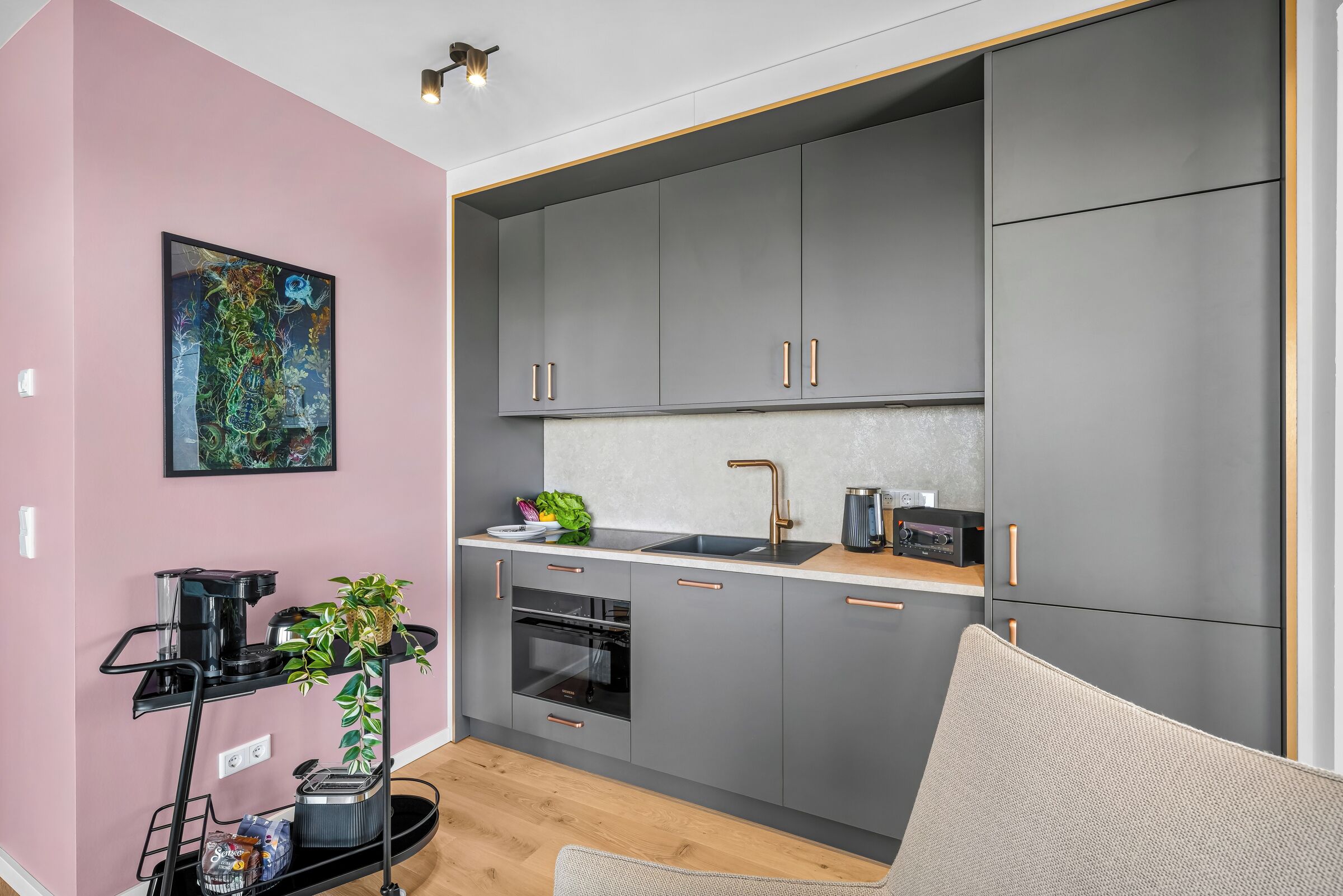 A modern kitchen with grey cabinets, a stainless steel sink, and a black coffee machine.