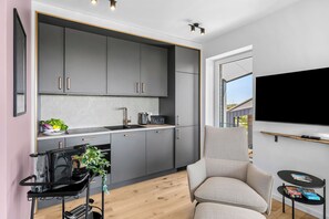 A modern kitchen with grey cabinets, a black countertop, and a built-in stove.