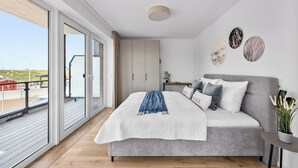 Een moderne slaapkamer met een groot bed, een balkon en uitzicht op het strand.