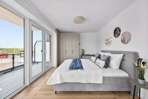 Ein modernes Schlafzimmer mit einem großen Bett, einem Balkon und Blick auf den Strand.