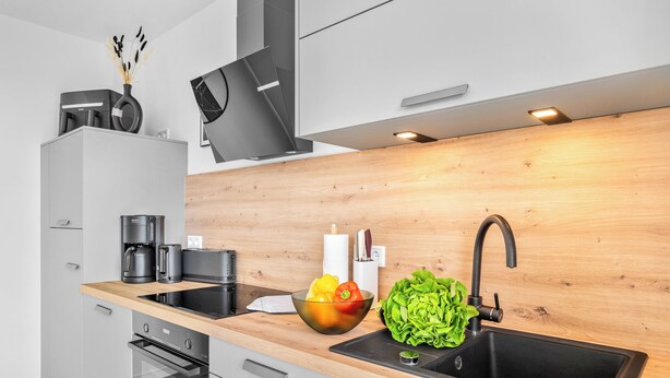 Een moderne keuken met een houten aanrecht, een inbouwoven, een koffieapparaat en een spoelbak.