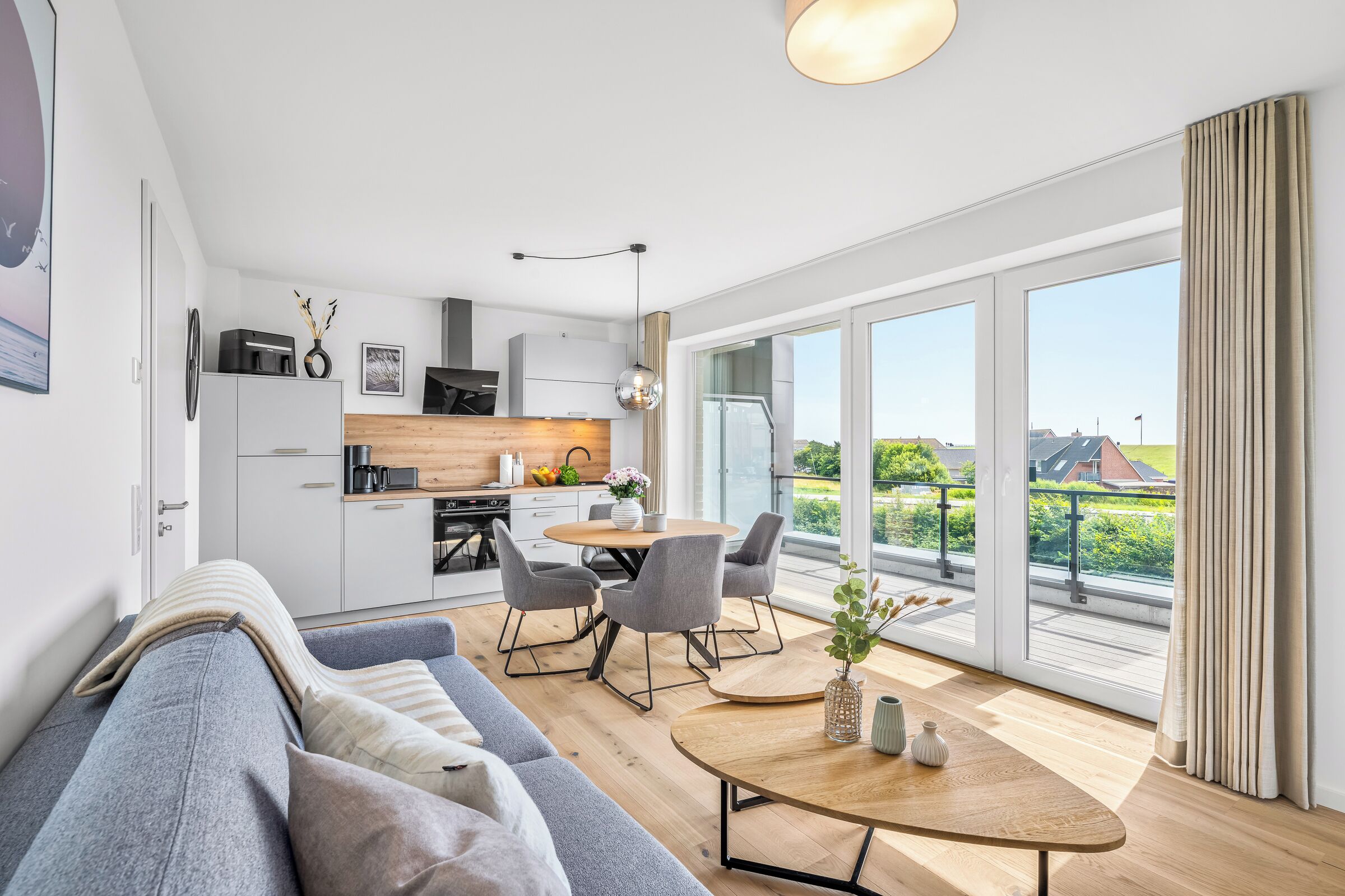Eine moderne Wohnung mit Küche, Essbereich und einem großen Balkon mit Blick.