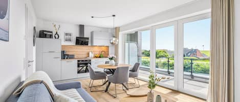 Eine moderne Wohnung mit Küche, Essbereich und einem großen Balkon mit Blick.