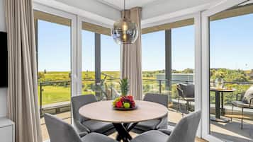 A modern dining area with a round table, grey upholstered chairs, and a central hanging light fixture.