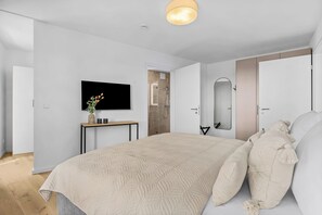A modern bedroom with a large bed, a flat-screen TV, a bedside table with a vase, and a mirror. - The View B07Johanna - common. Washing machine, balcony, elevator, parking space (Dagebüll)