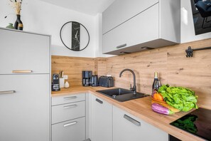 Une cuisine moderne avec un revêtement mural en bois, un évier noir et une machine à café.