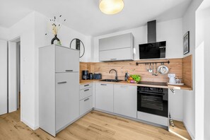 A modern kitchen with white cabinets, a wooden countertop, a built-in oven, and a microwave. - The View B07Johanna - common. Washing machine, balcony, elevator, parking space (Dagebüll)