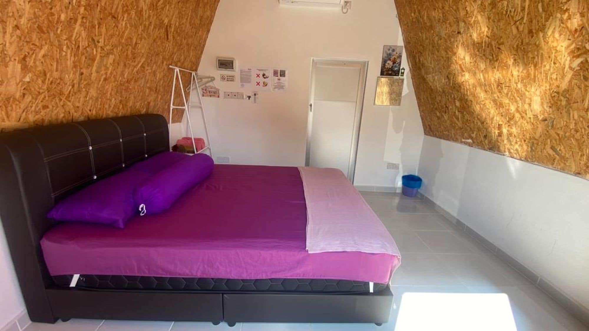 A bedroom with a bed, a wardrobe, a door, and a wall with a wooden texture.