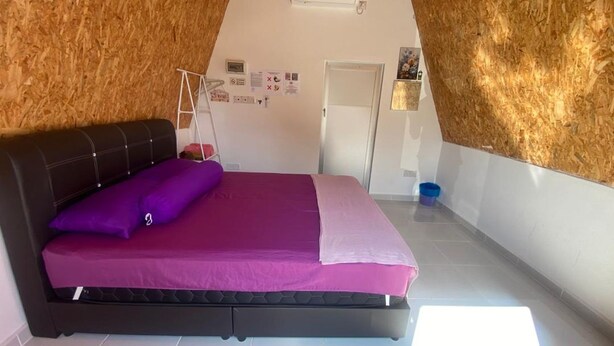 Un dormitorio con cama, armario, puerta y pared de madera.