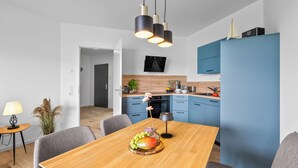 Eine moderne Küche mit blauen Schränken, einem Holztisch mit Obst und einer Pendelleuchte.