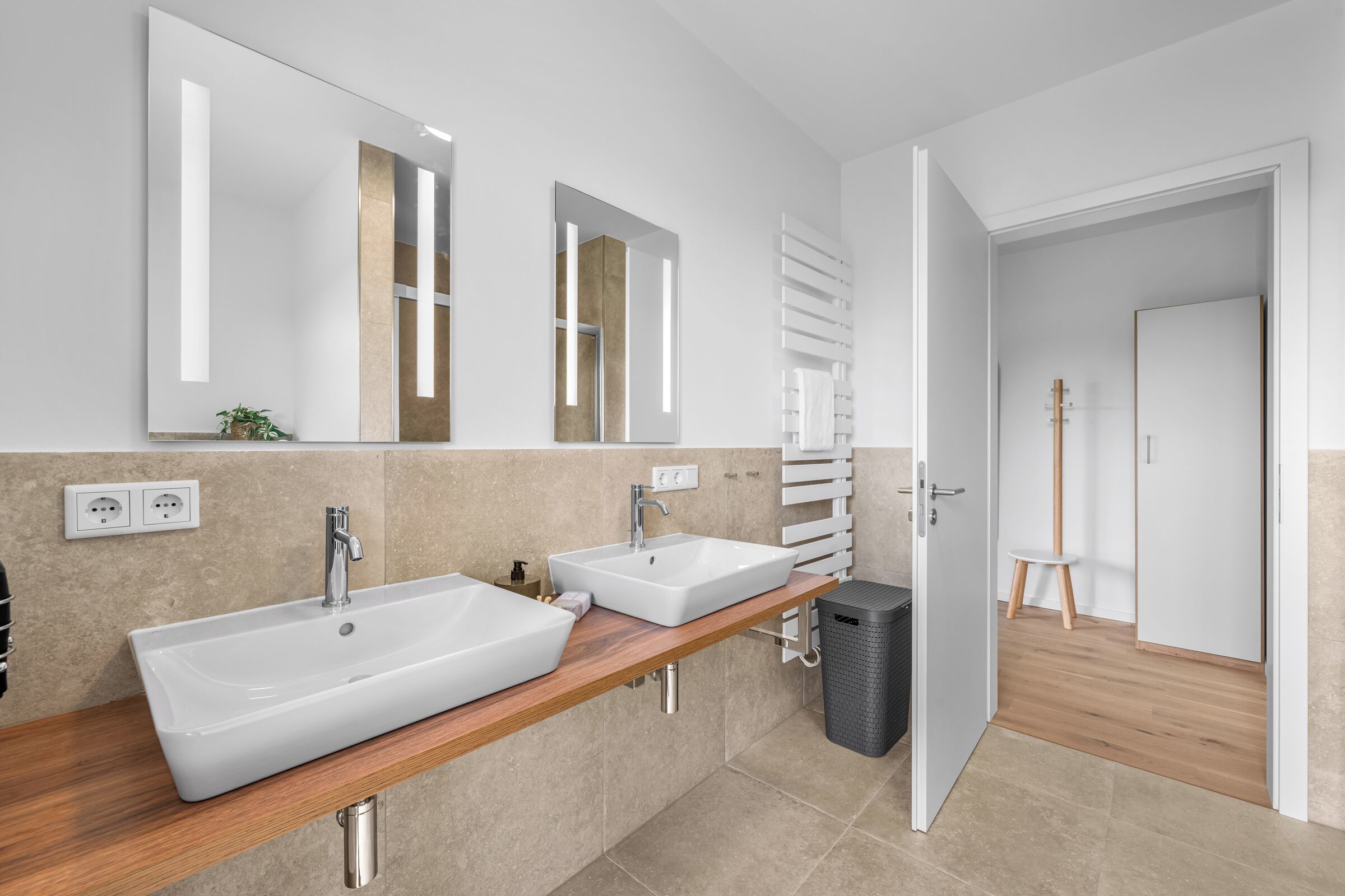 Ein modernes Badezimmer mit zwei Waschbecken, einem Spiegel und einem Handtuchhalter.
