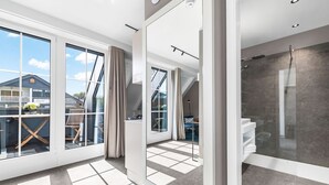Une chambre d’hôtel moderne dotée de grandes fenêtres, d’un balcon et d’un espace douche.