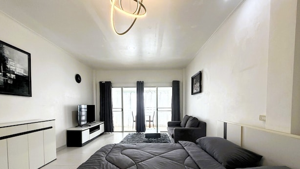 Una sala de estar moderna con una cama grande, un televisor, un sofá y un comedor con mesa y sillas.
