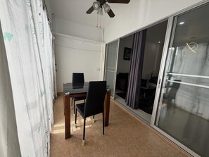 A room with a dining table, chairs, a ceiling fan, and large glass doors leading to an outdoor area. - Peaceful Pool-view Studio Near Jomtien Beach - Baan Suan Lalana (Pattaya)