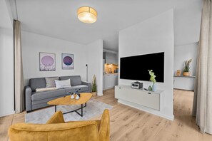 Ein modernes Wohnzimmer mit grauem Sofa, Couchtisch und Wand-Fernseher.