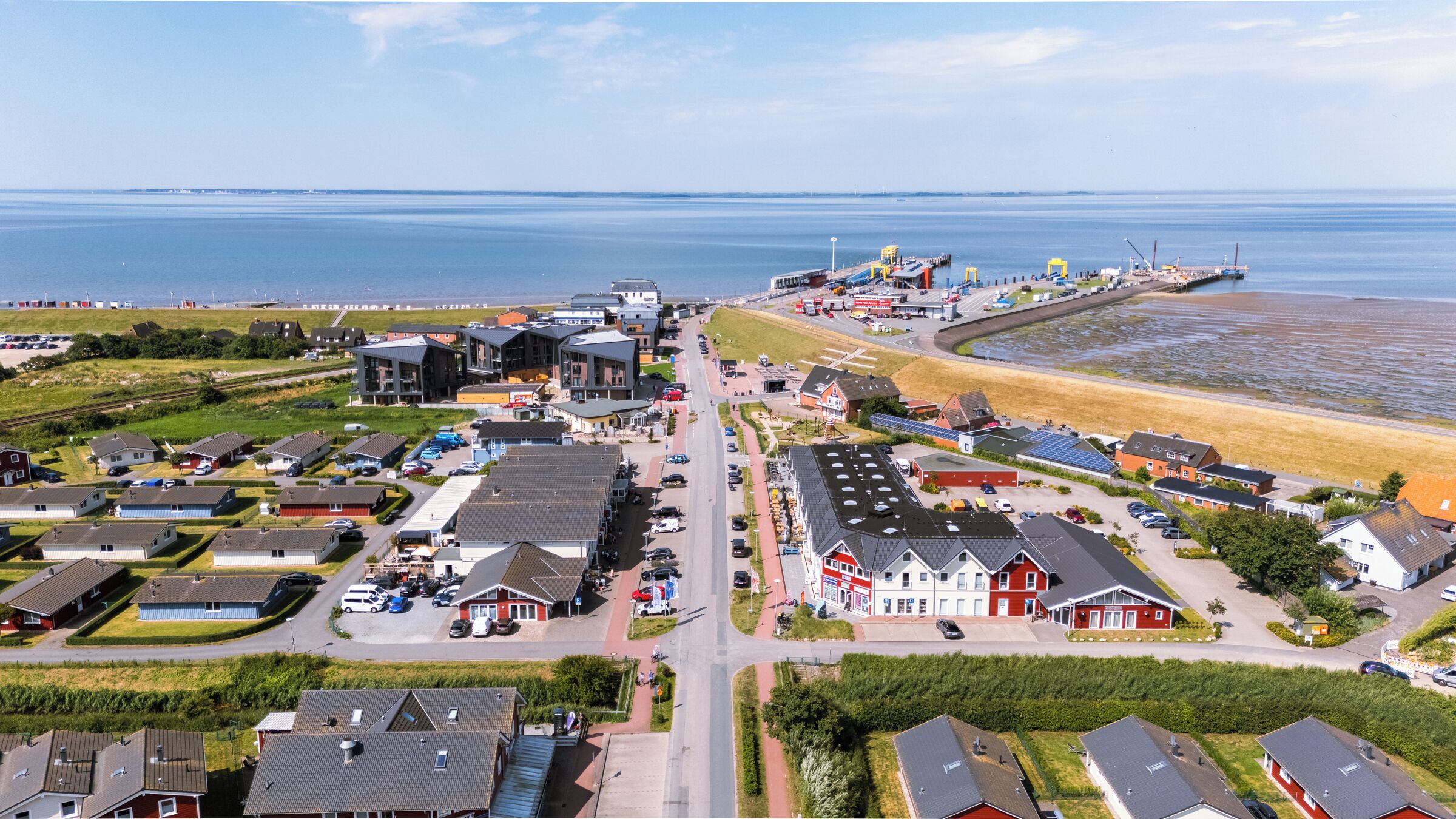 A coastal town with modern buildings, a beach, and a port.
