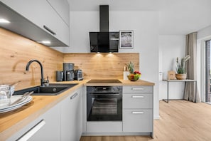 Eine moderne Küche mit einer Holz Arbeitsplatte, Edelstahlgeräten und einem eingebauten Ofen.