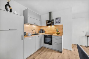 Eine moderne Küche mit weißen Schränken, einer Holz Arbeitsplatte, einem Einbauofen und einer Kaffeemaschine.