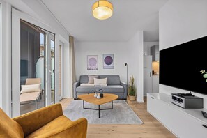 Ein modernes Wohnzimmer mit einer Couch, einem Couchtisch und einem Flachbildfernseher.