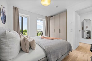 A bedroom with a bed, curtains, a window, a wardrobe, and a mirror. - The View C07 MeerTied  - Balcony, beach chair, barbecue, shared Sauna, car park (Dagebüll)