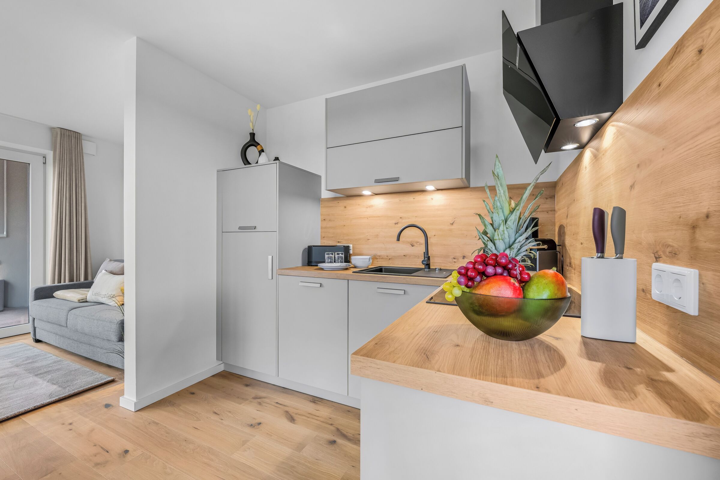 A modern kitchen with a wooden countertop, a sink, and a fruit bowl.