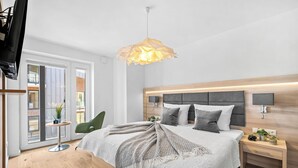 Ein modernes Schlafzimmer mit einem großen Bett, Nachttischen, einer Hängeleuchte und Blick ins Freie.